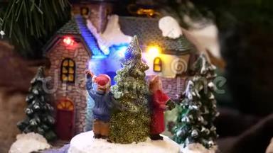 迷你圣诞节装饰的房子与跳舞的数字围绕圣诞杉木。